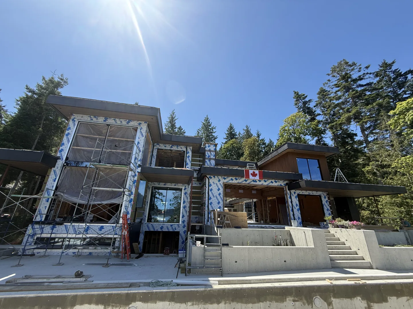 Timber-framed house under construction with tall glazed openings to the west elevation
